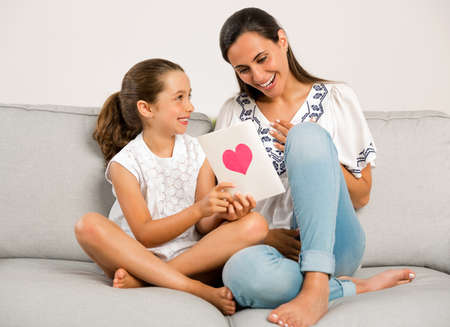 Mother receiving a greeting card on mother's day from her daughterの写真素材