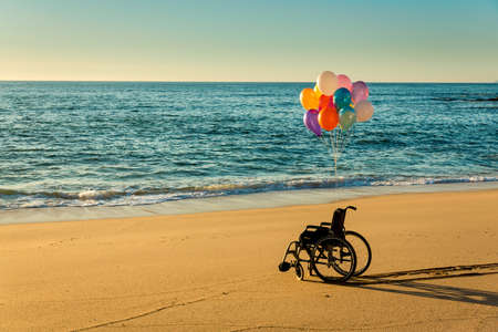 Wellchair on a beach with colored  ballons の写真素材