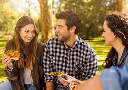 Friends at the park eating pizza