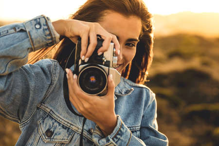 Beautiful woman taking picture outdoors with a analog cameraの写真素材