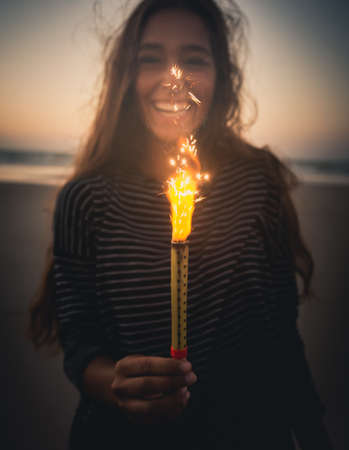 Teenage girl on the beach holding Fireworksの写真素材