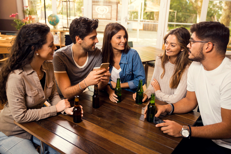 A group of friends at the bar drinking a beerの写真素材