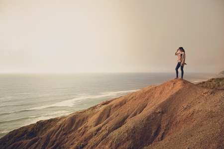 Woman on the top of a clif looking to the oceanの写真素材