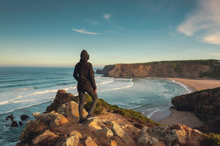 Woman looking to the ocean on a beautiful wild beach