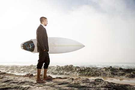 A Businessman holding is surfboard after a long day of workの写真素材