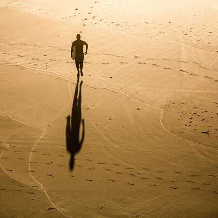 Top view of a surfer running on the beachの写真素材