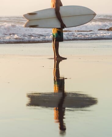 Surfer on the beach holding is surfboard and checking the waves