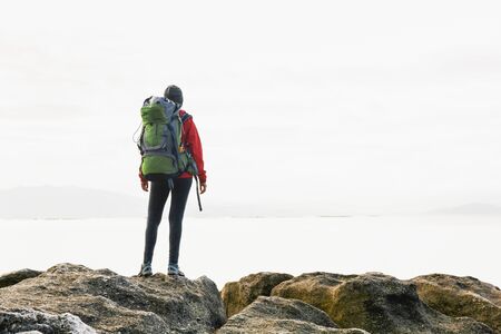 Woman with backoack enjoying the morning view of the coast