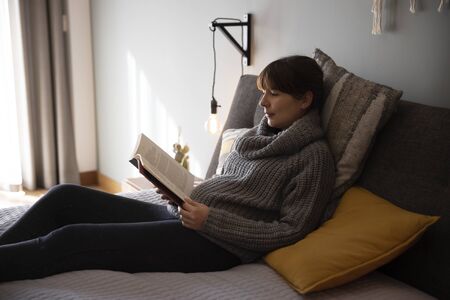 Beautiful woman on bed and reading a bookの写真素材