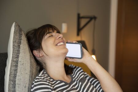 Woman on her bedroom, having a great chat at phone
