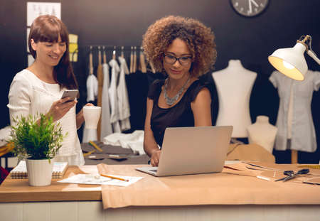 Two young entrepreneur women, and fashion designers working in their atelierの写真素材