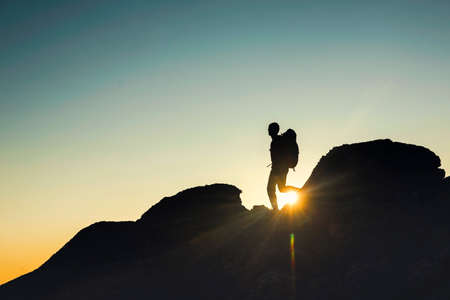 Shot of a man walking over the montains at sunsetの写真素材