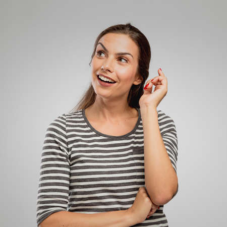 Portrait of a woman with a expression of having an idea. overa gray backgroundの写真素材
