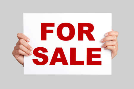 Female hands holding a billboard with the text For Saleの写真素材