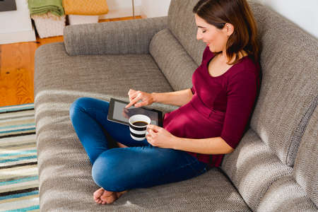 Beautiful woman at home in the sofa and working with a tabletの写真素材