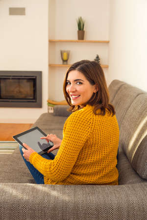 Beautiful young woman working with a tablet at homeの写真素材