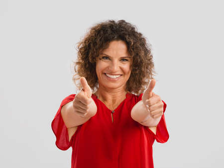 Portrait of a smiling middle aged brunette with thumbs upの写真素材