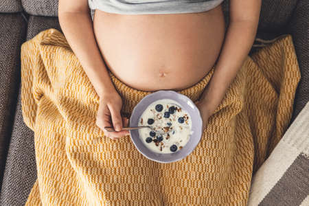 Pregnant woman eating healthy food at homeの写真素材