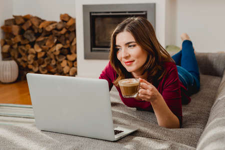 Beautiful woman at home working while drinking one capuchinoの写真素材