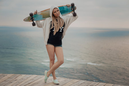Beautiful and fashion young woman posing with a skateboardの写真素材