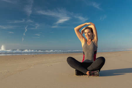 Shoot of a beautiful woman making stretching exercises in the beach
