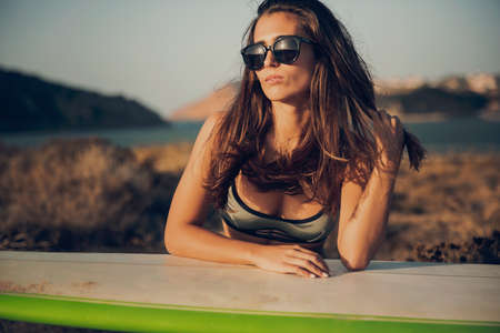 Beautiful young surfer girl posing with a surfboardの写真素材