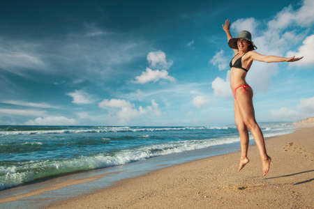 Beautiful woman in bikini jumping at the beachの写真素材