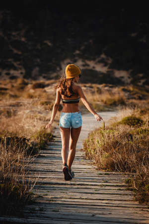 Beautiful young woman walking over a wood pathの写真素材