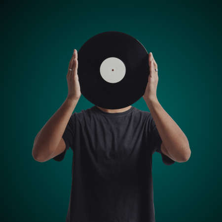 Young man olding a record in front of his faceの写真素材