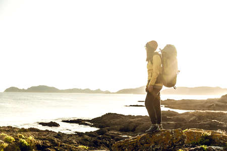 Shot of a woman exploring the coastline with backpackの写真素材