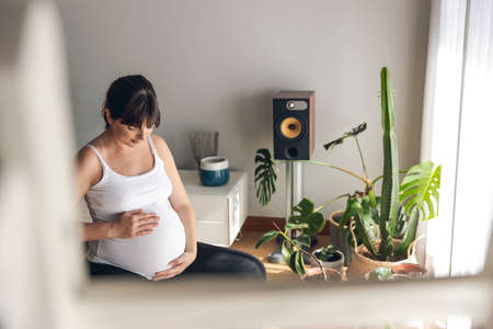 Pregnant woman working out at home doing breeding exercises. Keeping in good shape while waiting for babyの写真素材