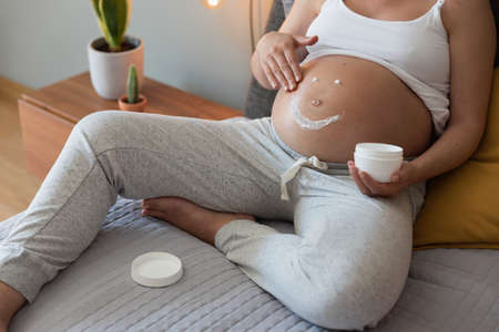 Pregnant woman applying stretch mark cream in her bellyの写真素材