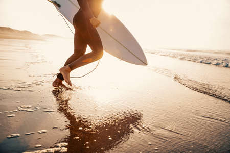A surfer with his surfboard running to the waves
