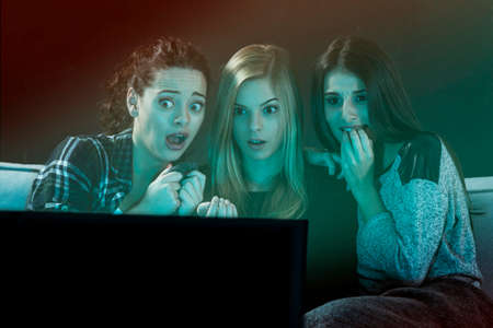 Teenage girls watching horror movie with popcornの写真素材