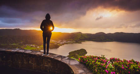 Back view of a woman looking to a beautiful sunset in AÃ§ores, Portugal