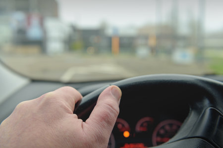 Windshield and perspective of the road. Steering. Selected Focus. Hand on a car steering wheel
