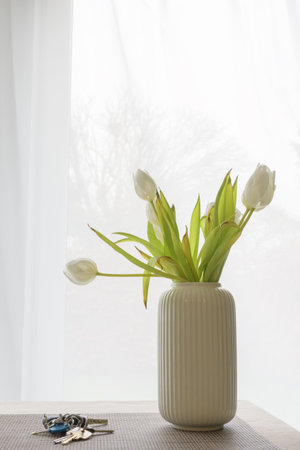 flowers withering  in a vase and keys left on the table. Concept vertical formatの写真素材