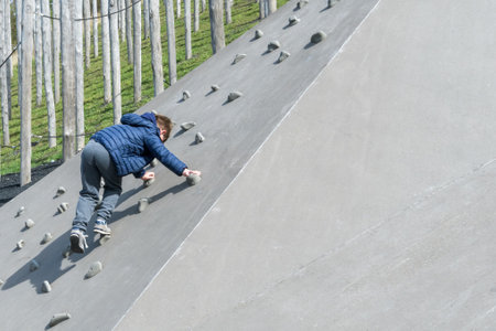 A boy climbs a wall in the children's play park outsideの写真素材