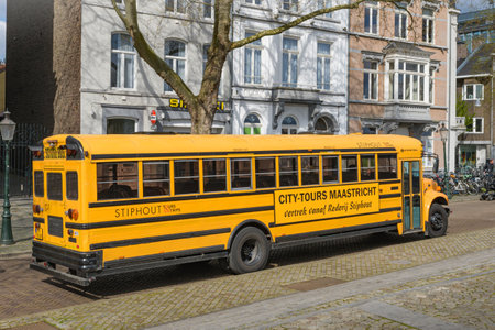 Maastricht. Limburg - Netherlands 10-04-2022. Classic yellow school bus adapted for tourist trips in the centrum of Maastrichtのeditorial素材