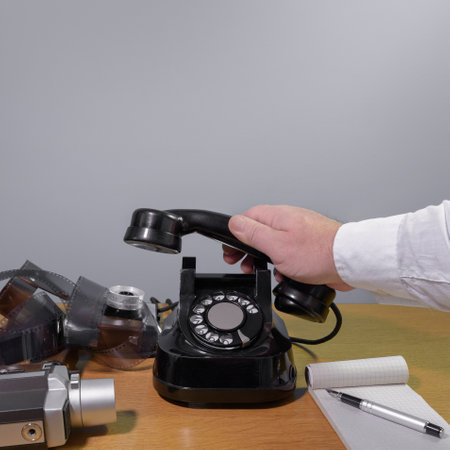 The hand of a journalist reaches for the phone. Old telephone set on a wooden table, retro...