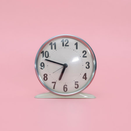 A white retro alarm clock without an external bell. isolated on pink background. Square format