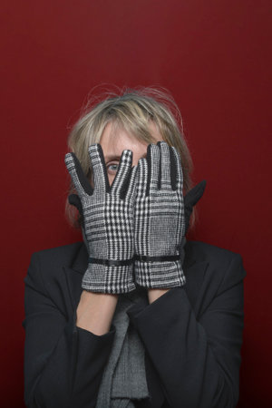 Turn a blind eye. A female model in elegant gloves looks through her fingers at the camera. portrait...