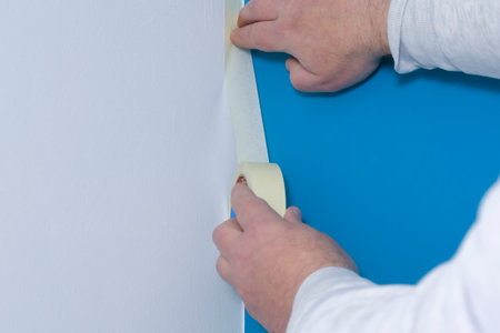 Applying masking tape to be painted. Border of white and blue on the wallsの写真素材