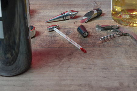 Bottled wine set from accessories. Additional stoppers, means for opening, a corkscrew and thermometer. On the texture table. Closeup.の写真素材