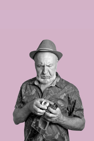 Elderly man with a film camera. The old man tries to remember the settings of the film camera. Retro...