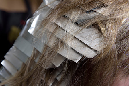 The technique used when using professional coloring to cover gray roots involves putting the foil between rows of hair.の写真素材