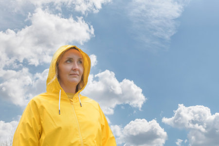 Portrait of a girl dressed in a yellow jacket with a hood on her head and looking into the distance...