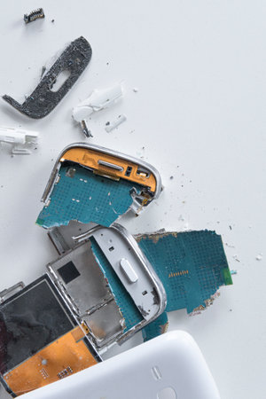 Broken smartphone on white table. Vertical. The insides of a dropped smartphone in a white case....