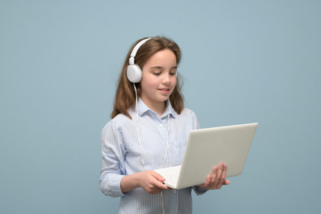 Portrait of a young girl with a small white laptop and white headphones. pastel aquamarine backgroundの写真素材