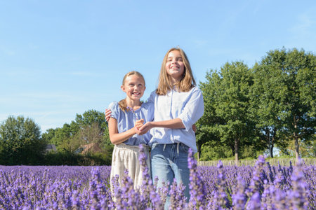 Two teen girlfriends on blooming lavender. Laughing, enjoying summer holidaysの写真素材